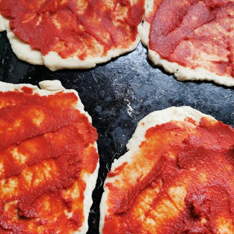 Mini pizza bases spread with tomato purée 