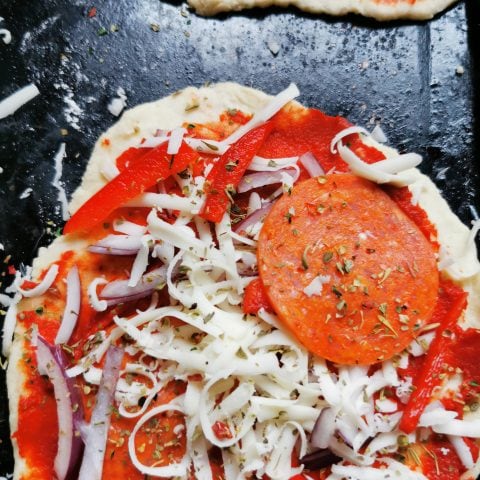 A scone dough pizza topped with pepperoni, cheese and red peppers 