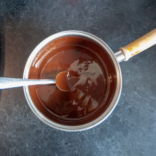 A saucepan of melted butter and chocolate on a dark backgound