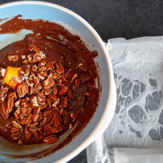 A bowl of brownie batter with chopped pecan nuts.