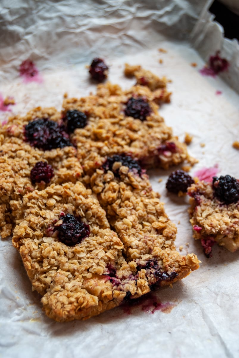 Apple and blackberry flapjacks on a sheet of baking parchment.