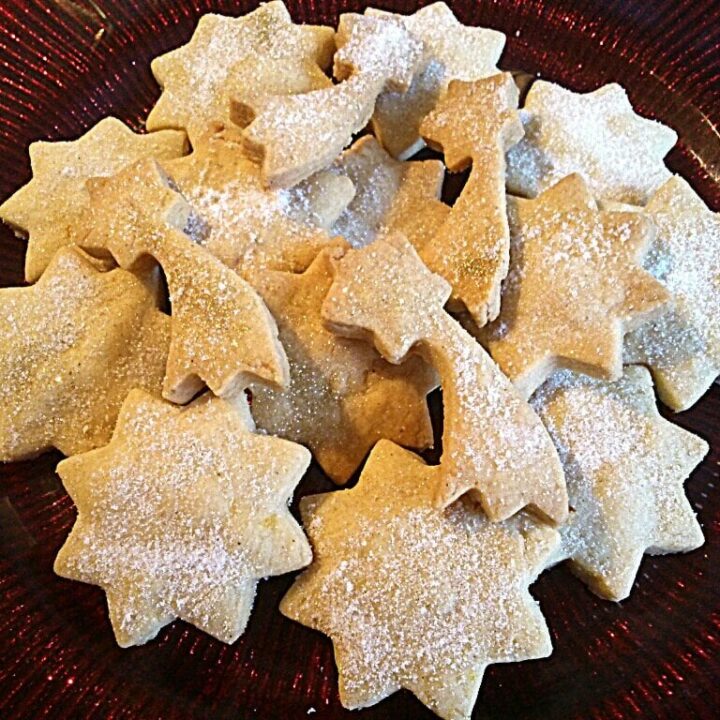 a red plate with sugar dusted shortbread star biscuits.