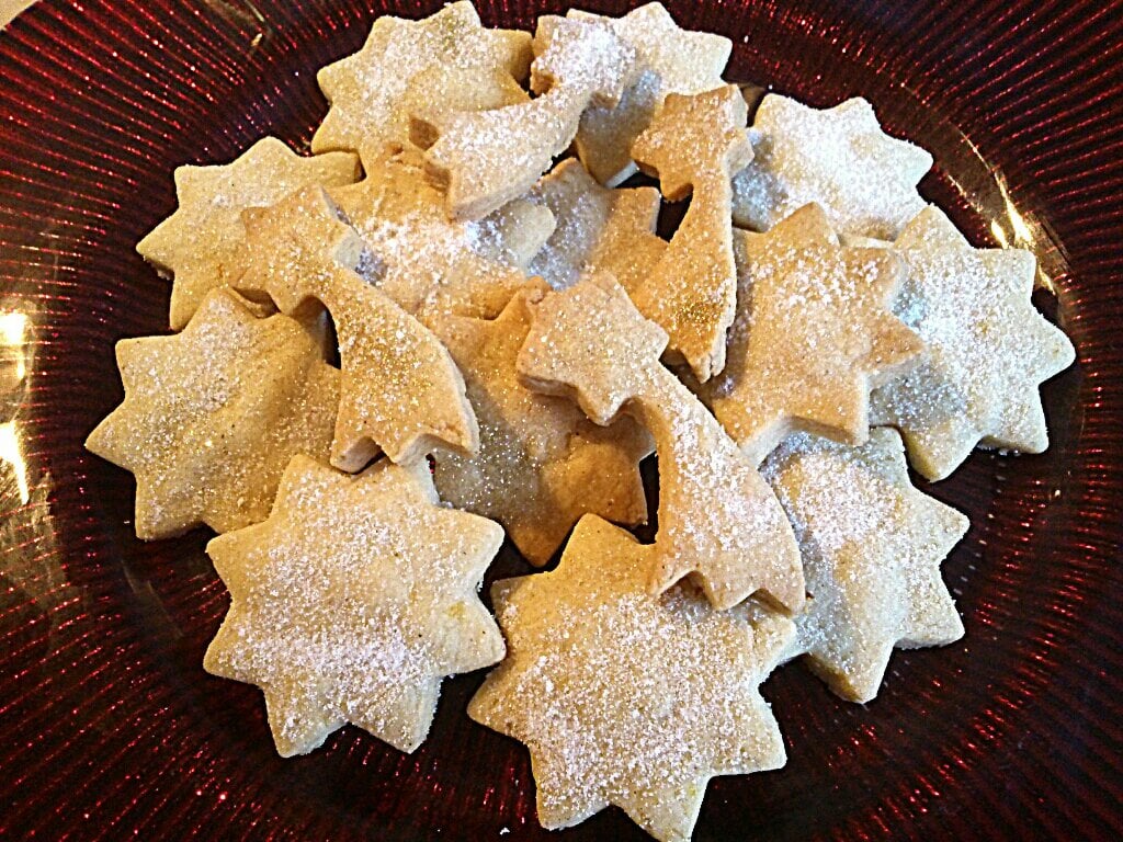 a red plate with sugar dusted shortbread star biscuits.