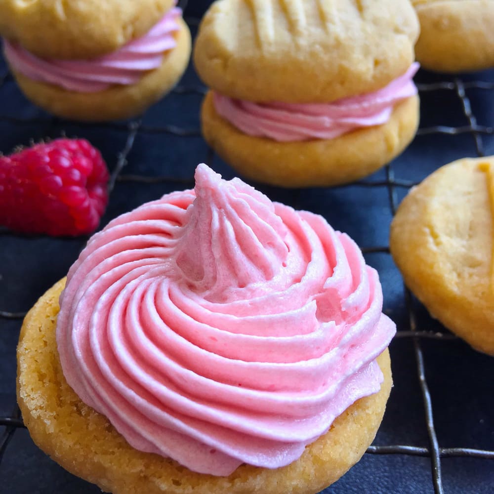 A custard biscuit topped with a pink raspberry buttercream