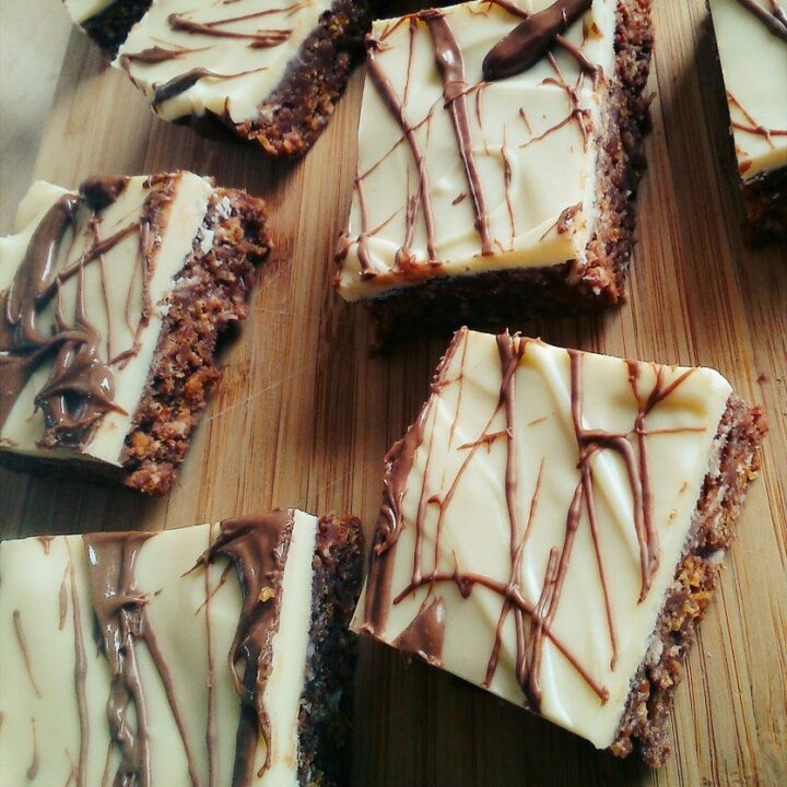 Cornflake bars topped with a white chocolate layer and a drizzle of milk chocolate on a wooden board