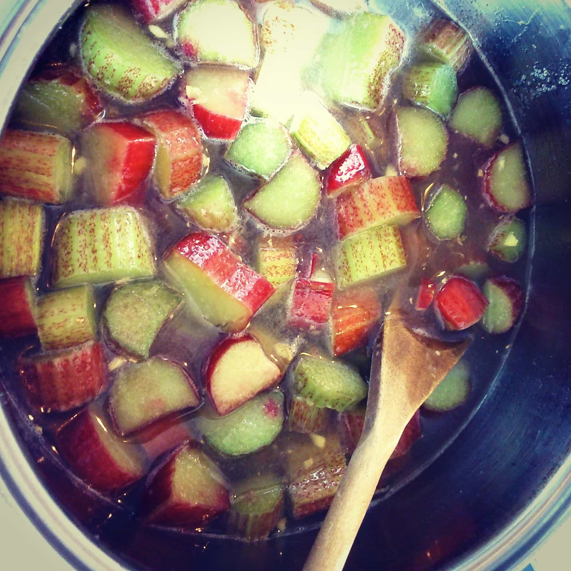 a close up picture of a saucepan of chopped rhubarb and a wooden spoon.