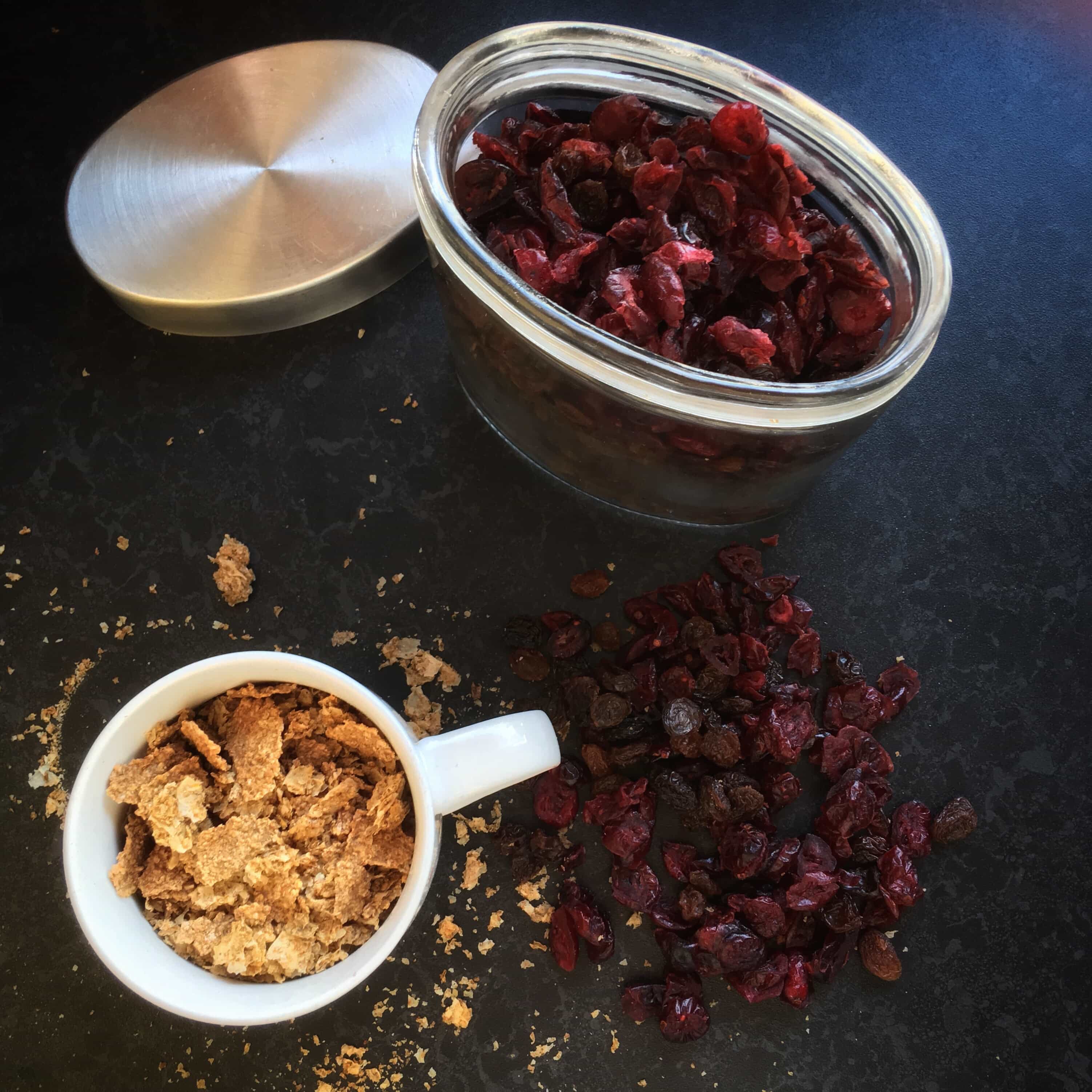 A cup of bran flakes and a jar of cranberries