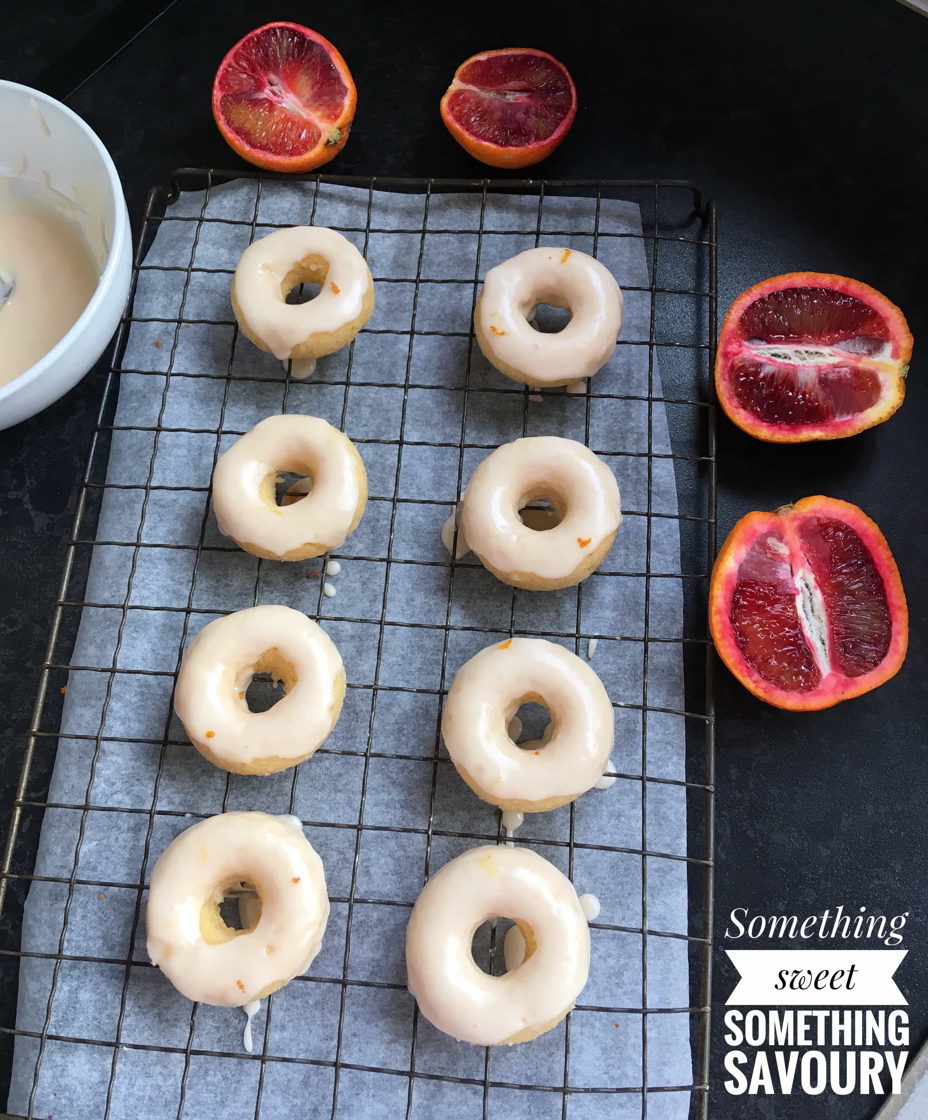 mini baked vanilla donuts with blood orange glaze on a wire rack. 