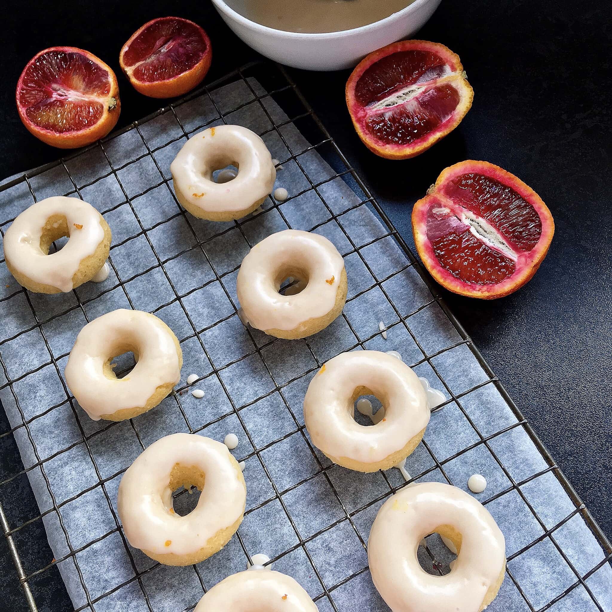 mini baked vanilla donuts with blood orange glaze on a wire rack. 