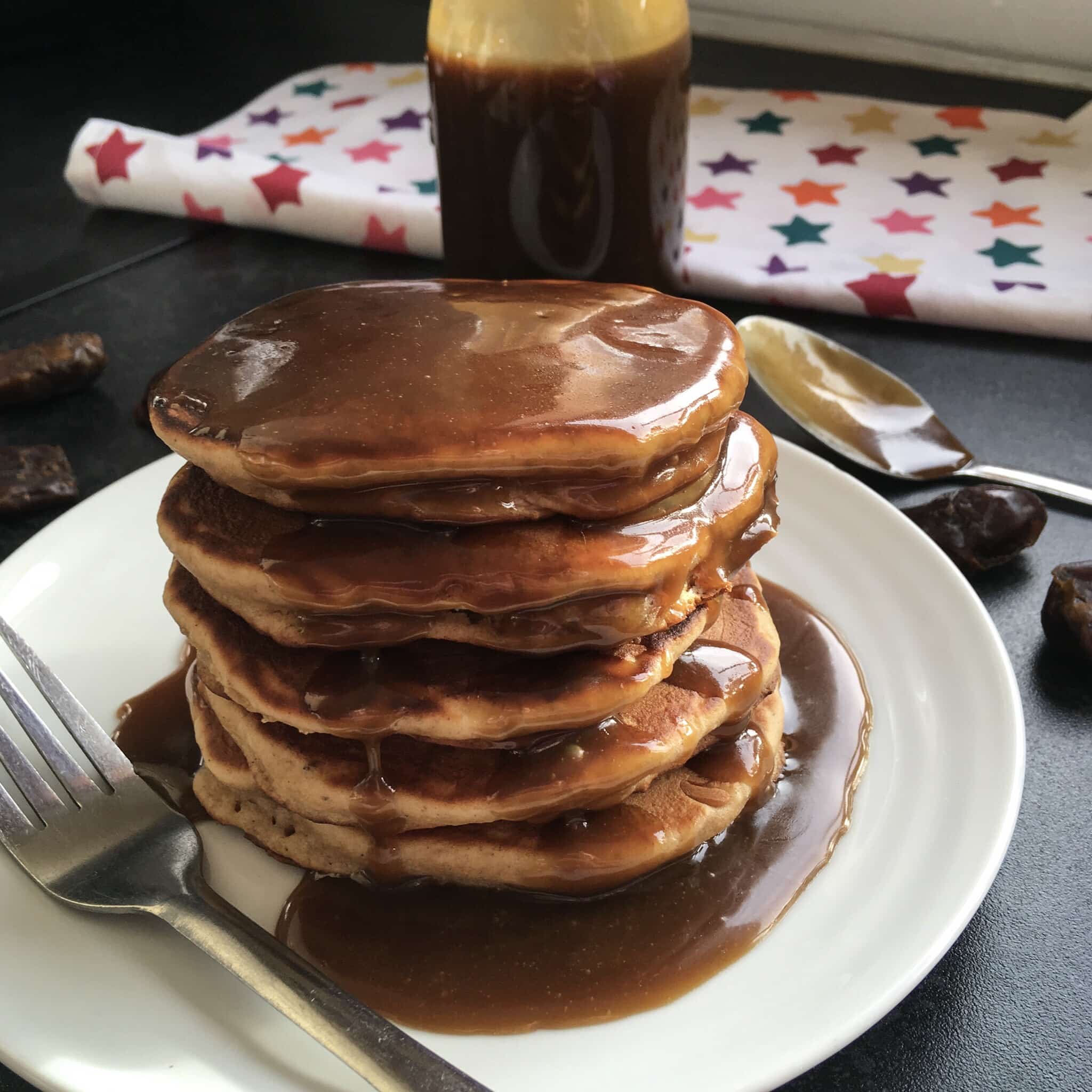 A stack of sticky toffee pudding pancakes smoothered in a rich toffee sauce