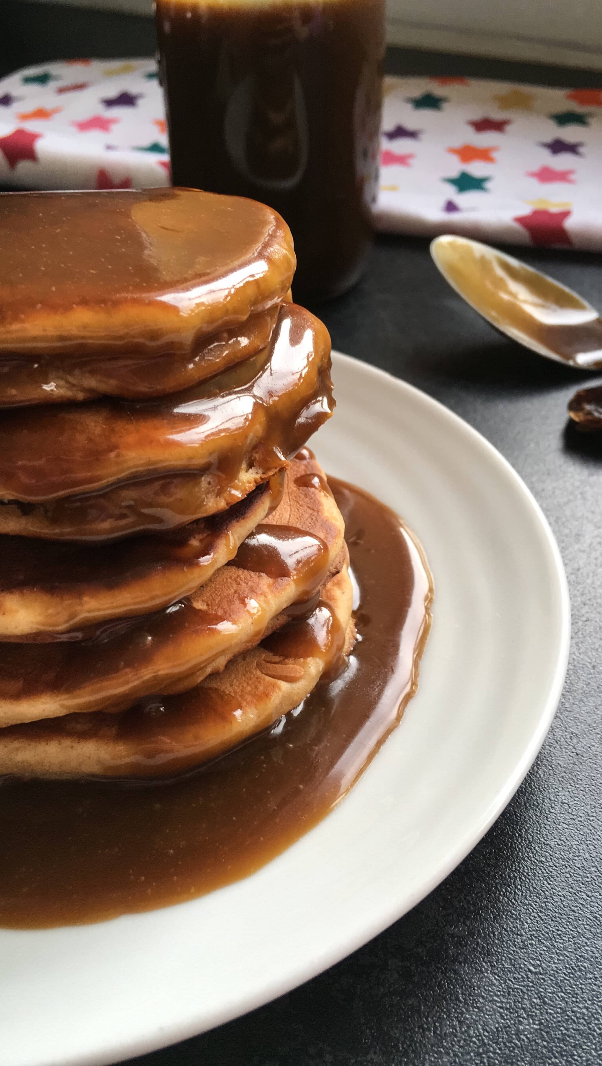 A close up picture of a stack of pancakes covered in a rich toffee sauce.