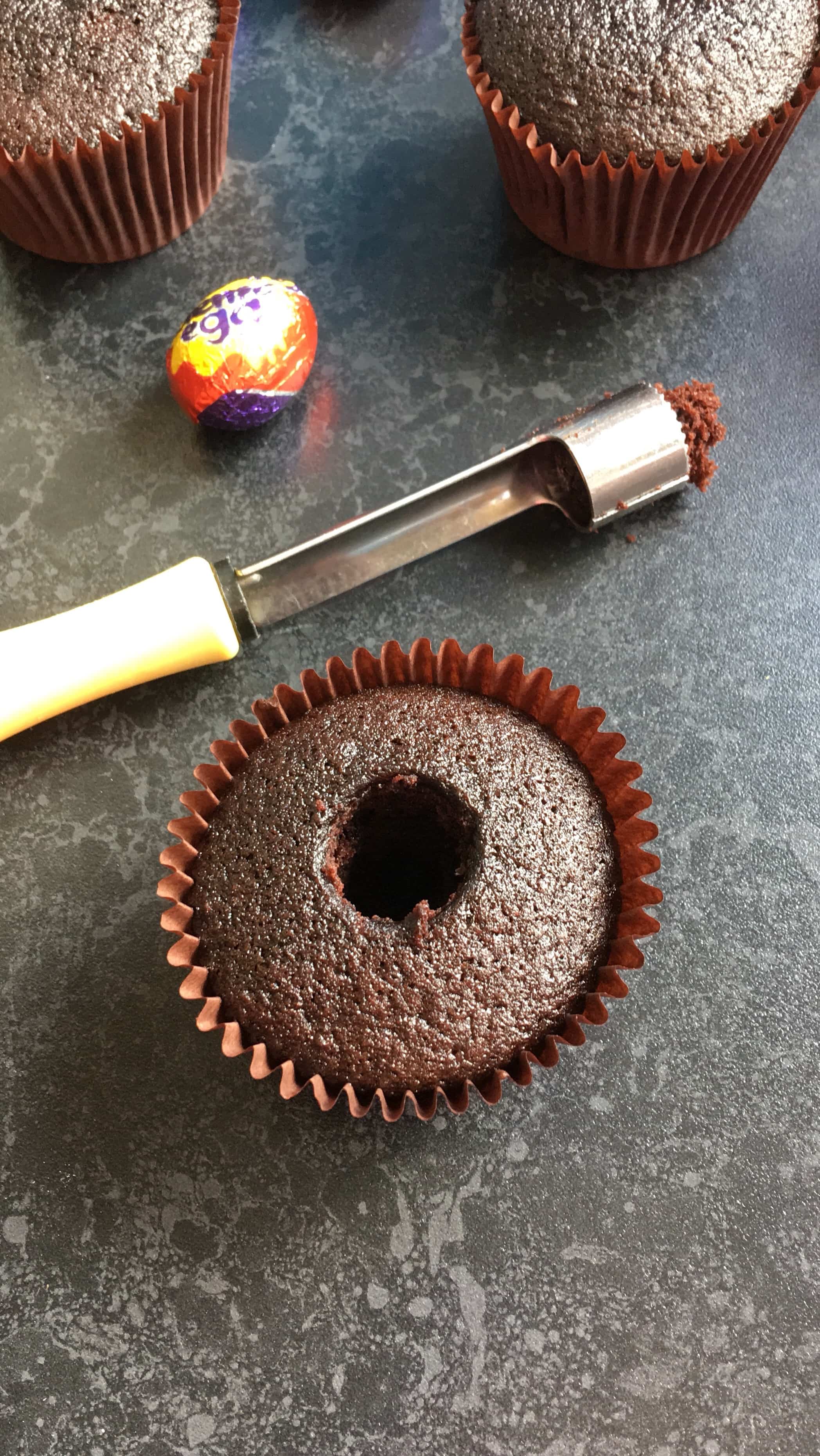 A chocolate cupcake with the middle cut out of it using an apple corer