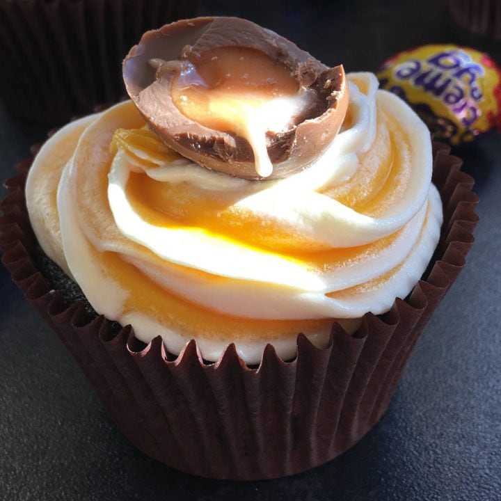 A photo of a creme egg cupcake topped with a mini halved creme egg