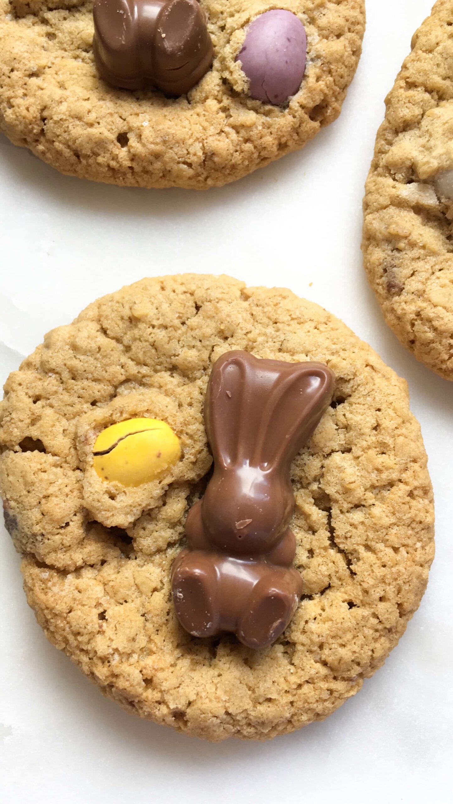 A picture of cookies topped with mini Easter eggs and chocolate bunnies on a white backdrop