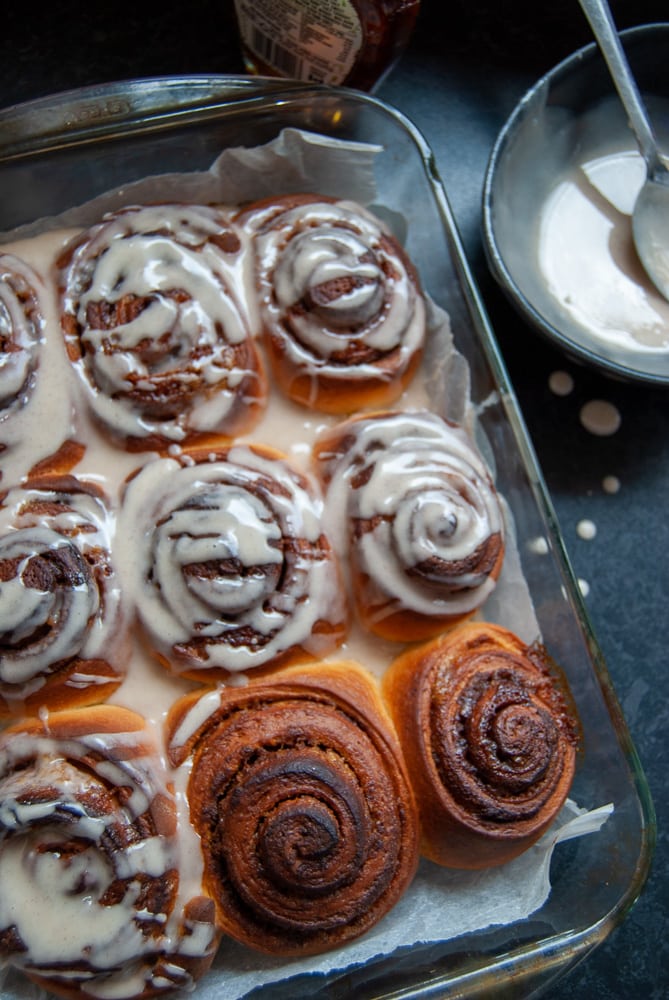 A freshly baked tray of cinnamon rolls covered in maple glaze.