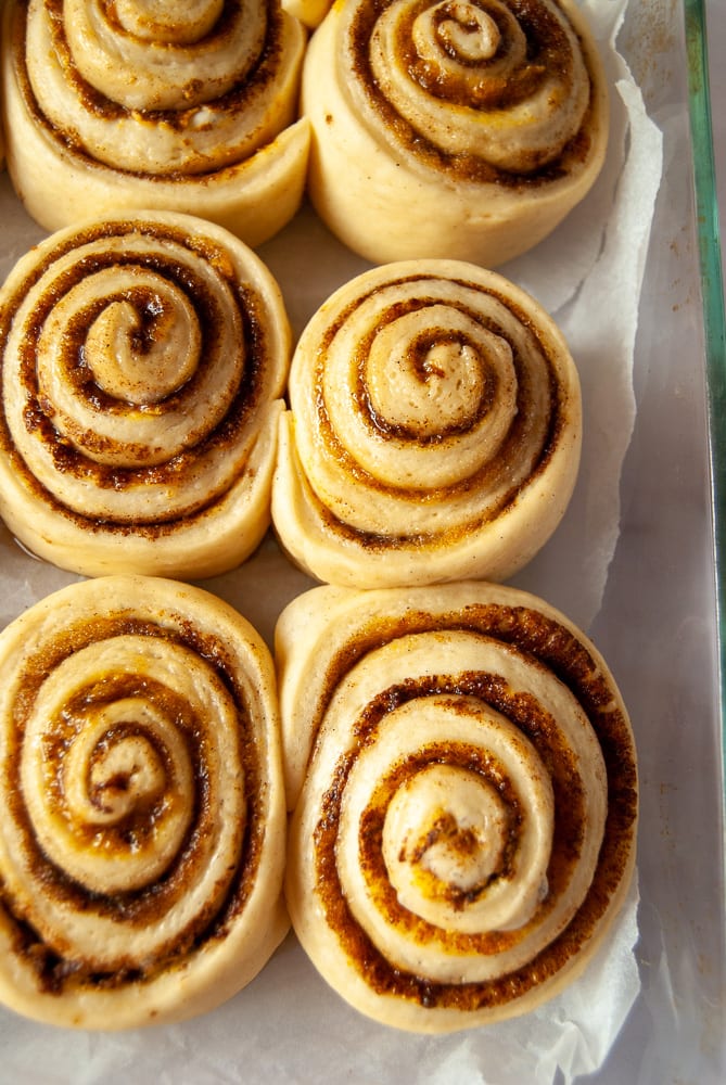 A tray of unbaked cinnamon rolls with a pumpkin spice filling