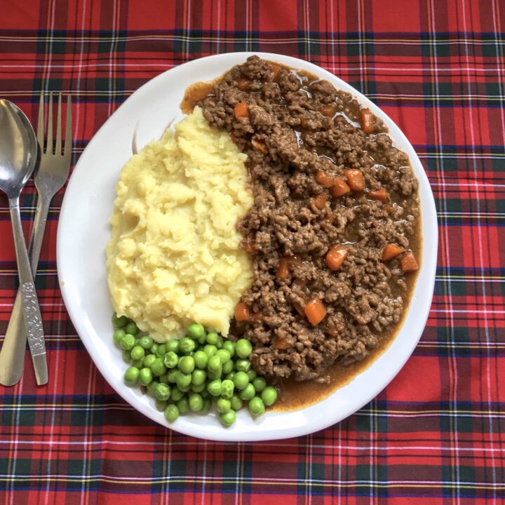 A white plate of mince, tatties and peas on a tartan tablecloth