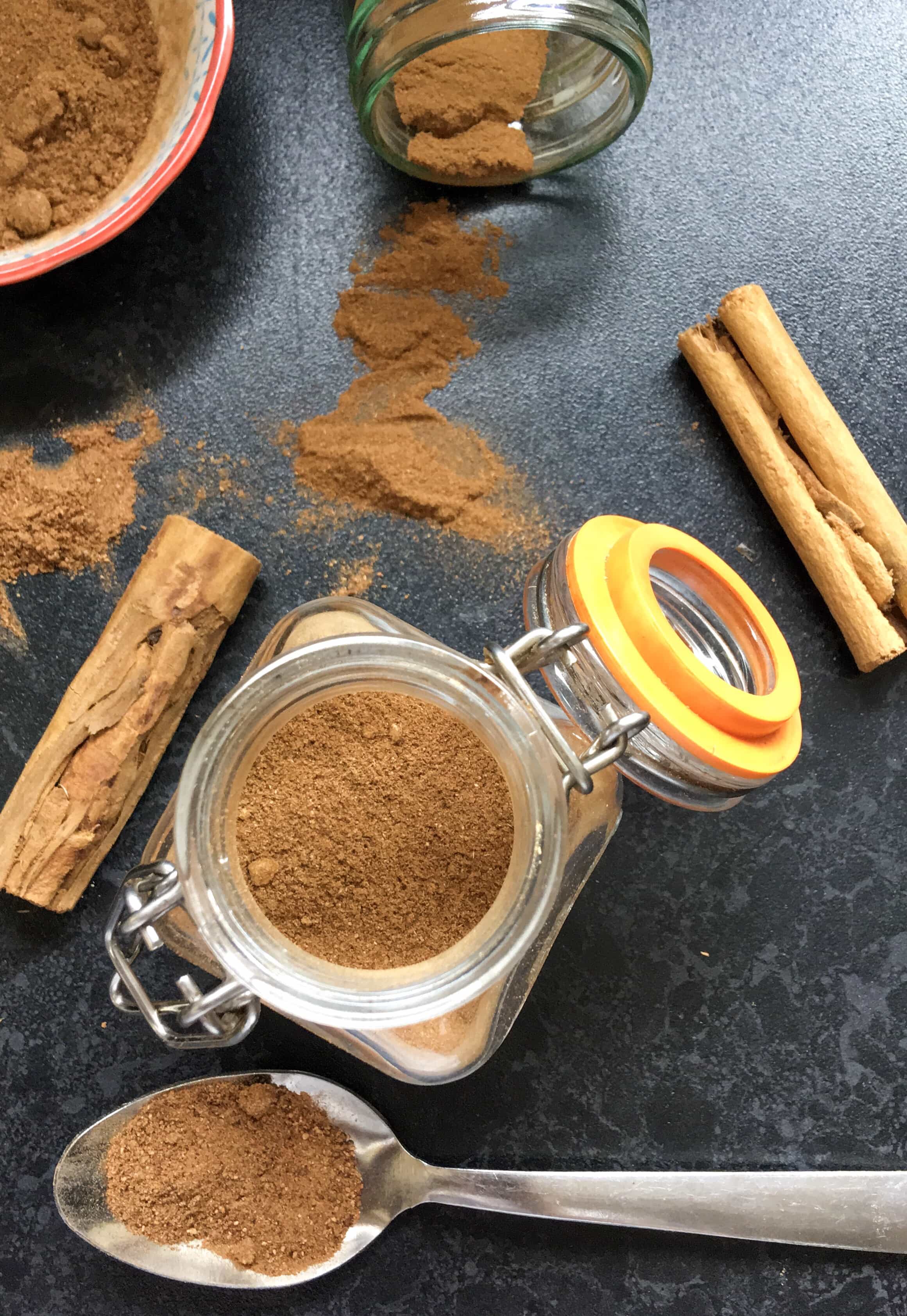 A flatlay photo of an open kilner jar of homemade pumpkin spice and cinnamon sticks