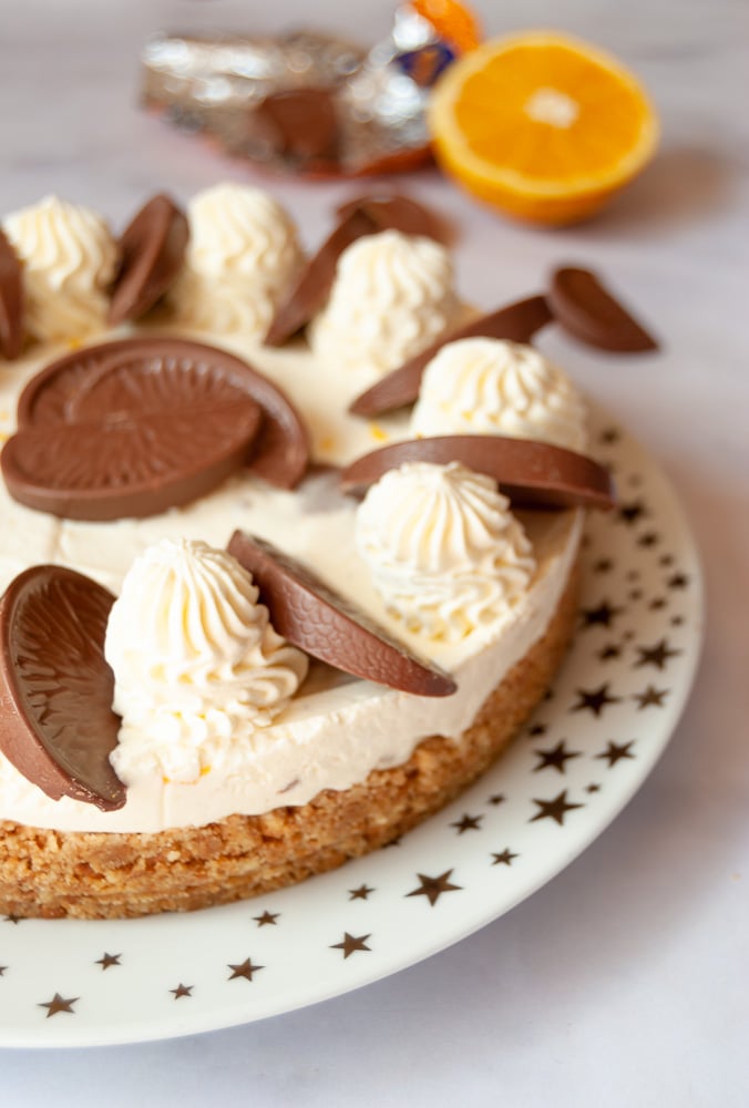 A close up photo of a no bake Terry's chocolate orange cheesecake on a gold and white star plate