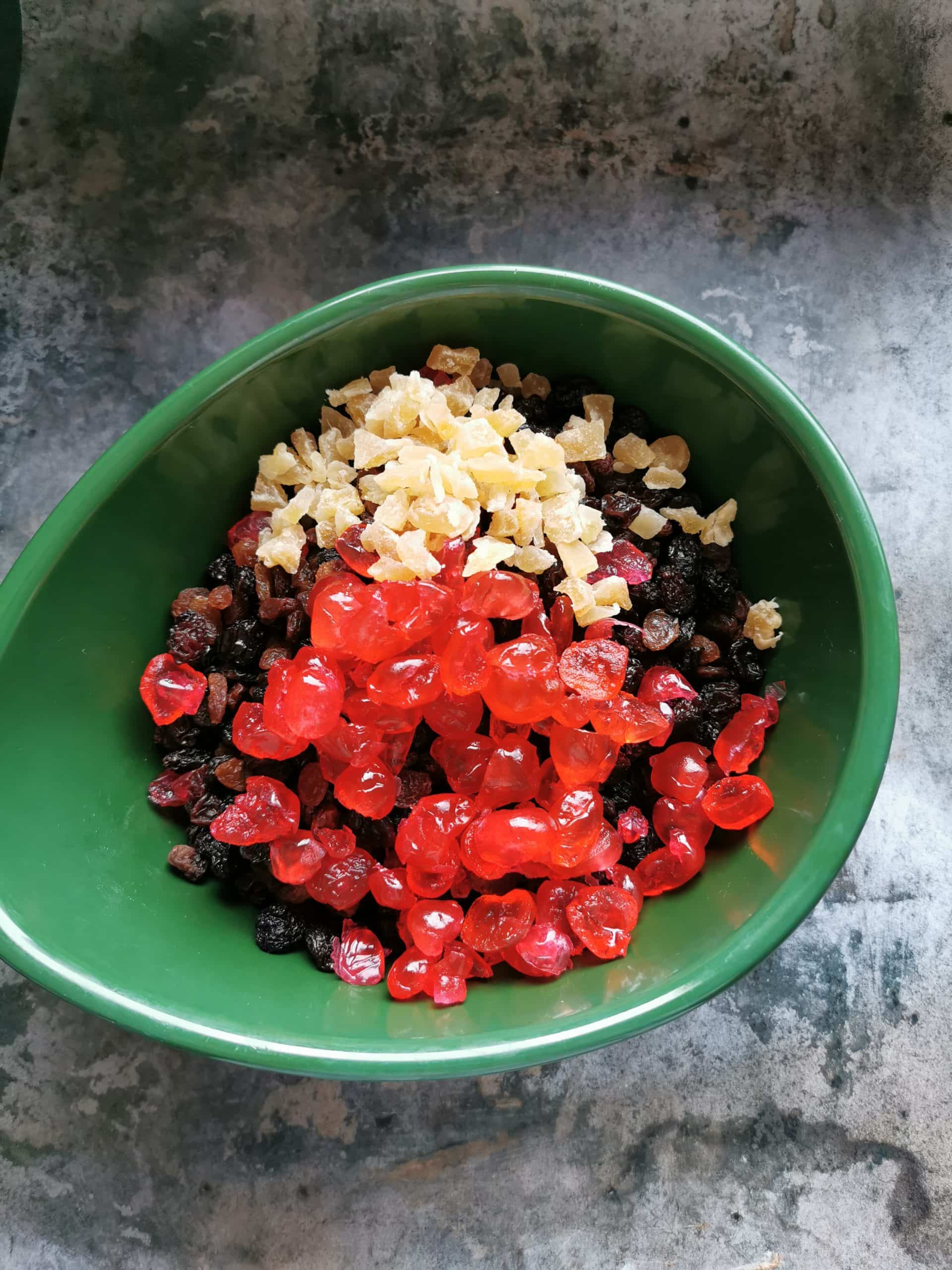A green bowl of mixed dried fruit for making fruit cake