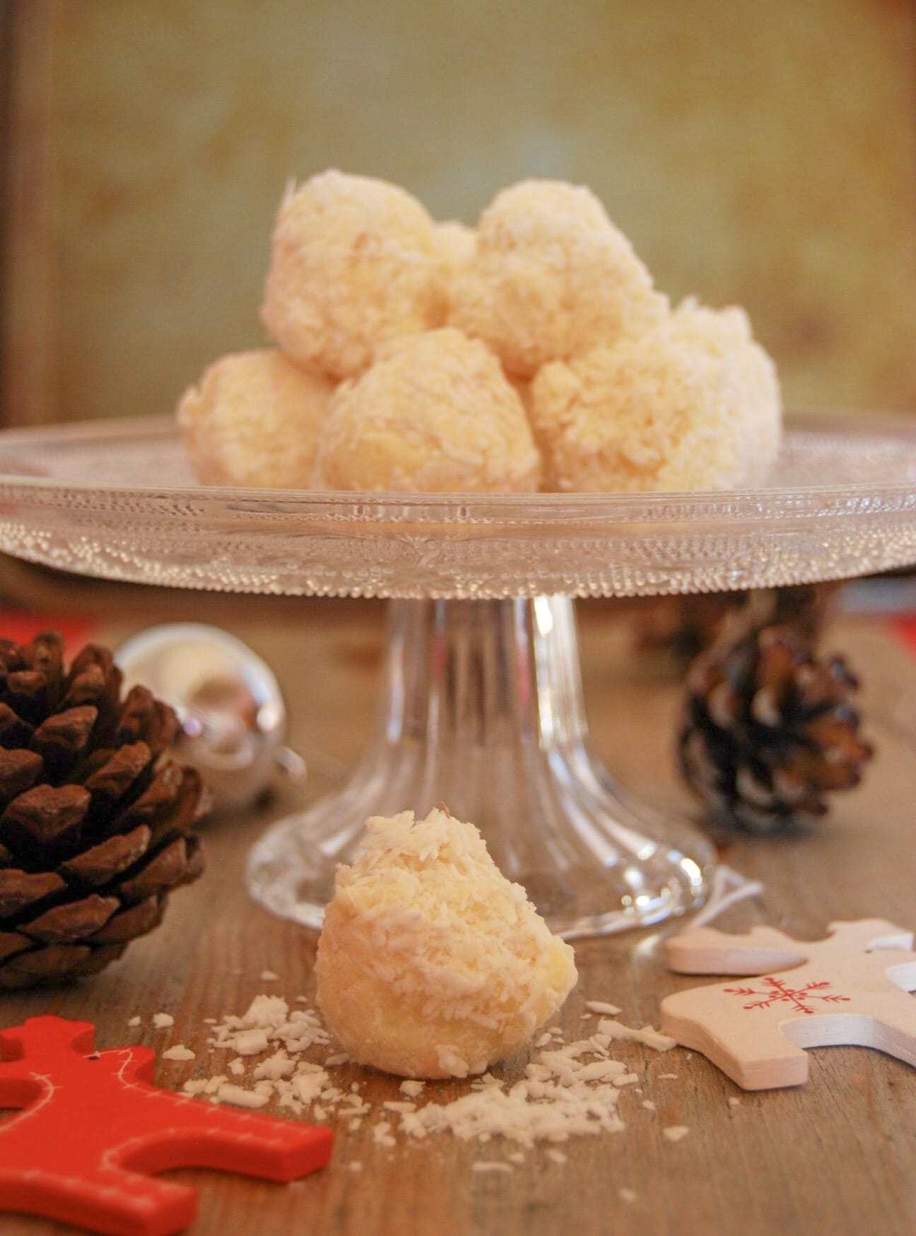 A vintage glass cake stand with white chocolate coconut truffles and Christmas decorations 