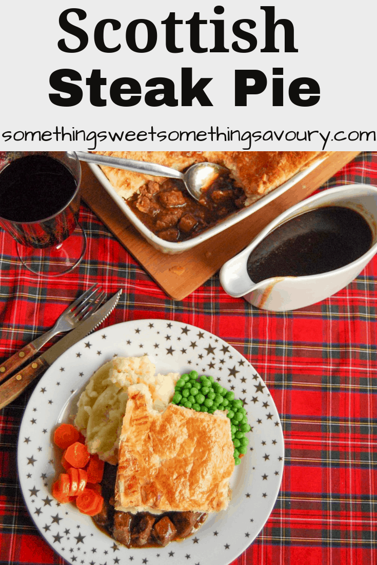 A flatlay photo of a gold and white star plate of steak pie with a puff pastry lid and beef chunks in gravy with mashed potatoes, peas and carrots. A jug of gravy and a large steak pie can also be seen in the top of the photo.