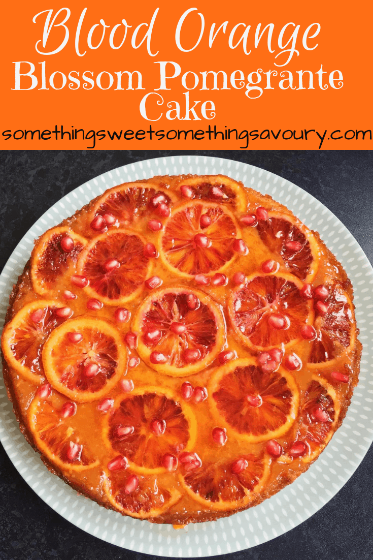 A flat lay photo of a blood orange blossom pomegranate cake on a white and green plate.