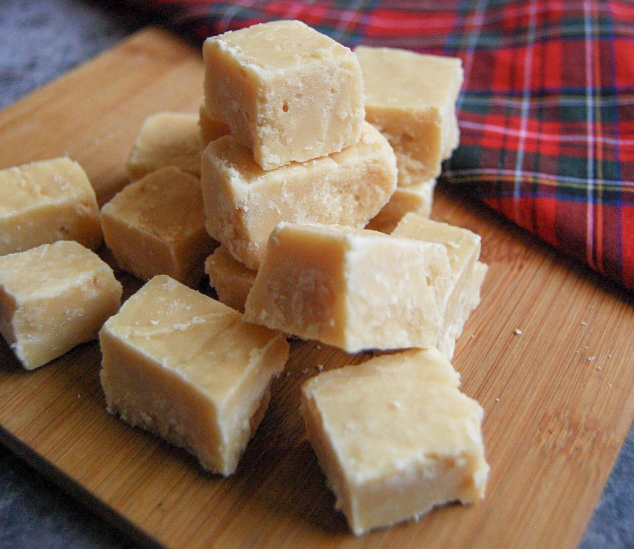 Pieces of Tablet sitting on a wooden board with a tartan cloth in the background