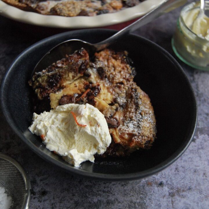 A bowl of chocolate orange panettone bread pudding with whipped cream.