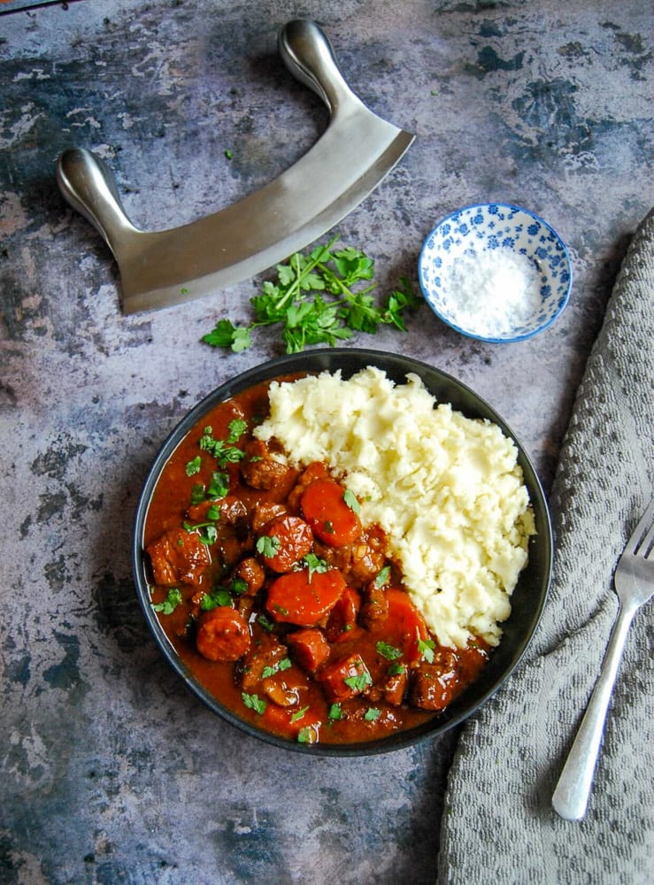 A flaylay photo of a plate of slow cooker beef and chorizo casserole on a marbled grey background