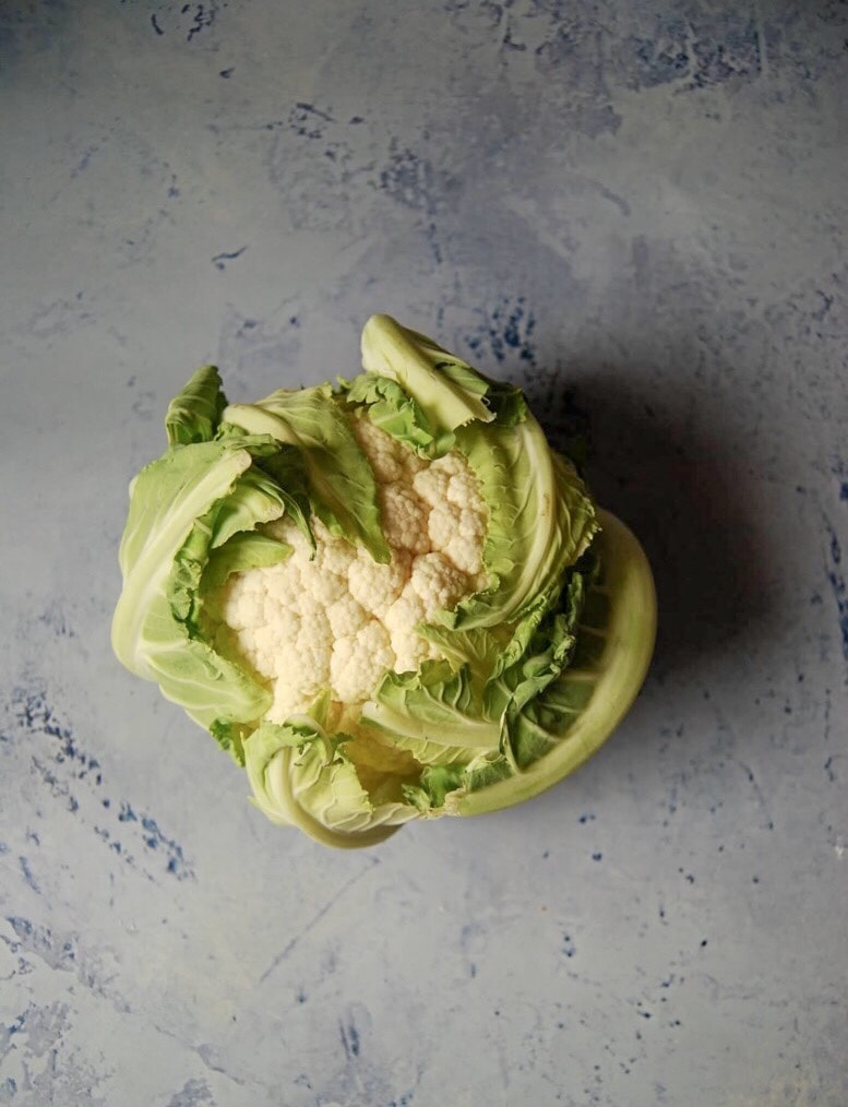 A photo of a cauliflower on a light blue background.