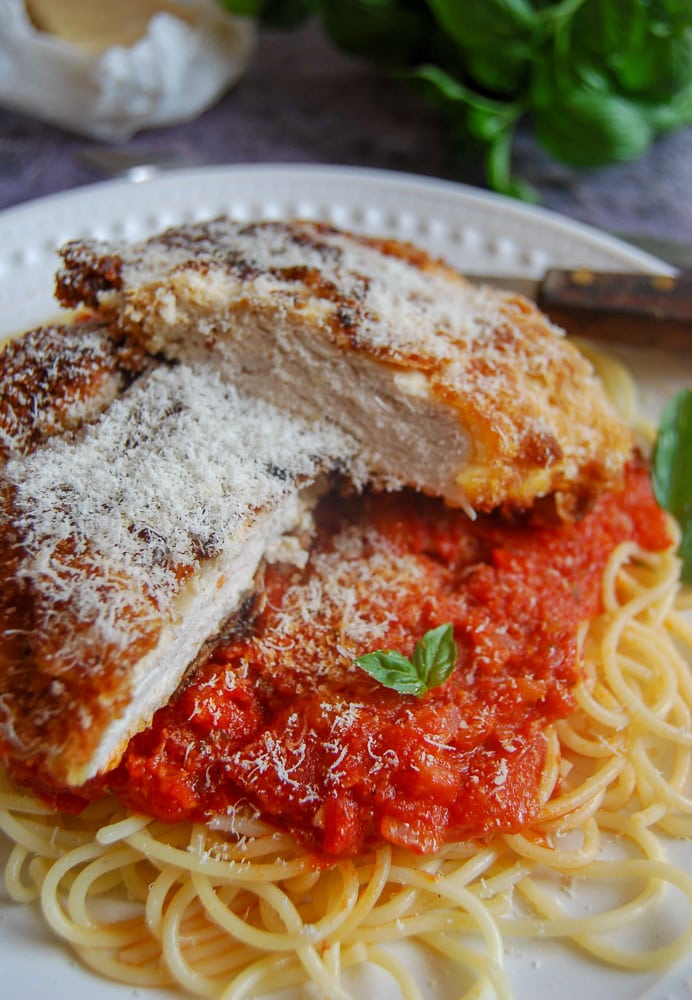 A plate of chicken Milanese with Spaghetti and tomato sauce on a white plate. 