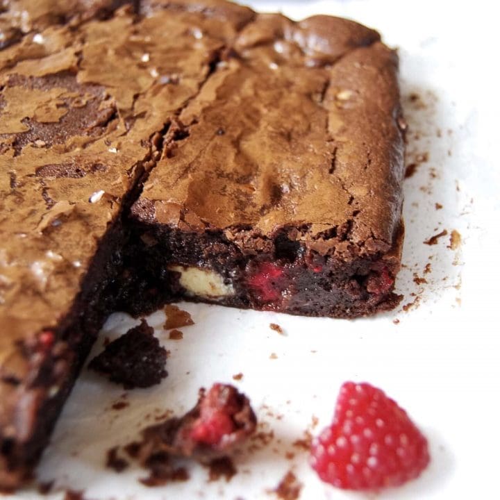 A slab of white chocolate and raspberry brownies on a white background