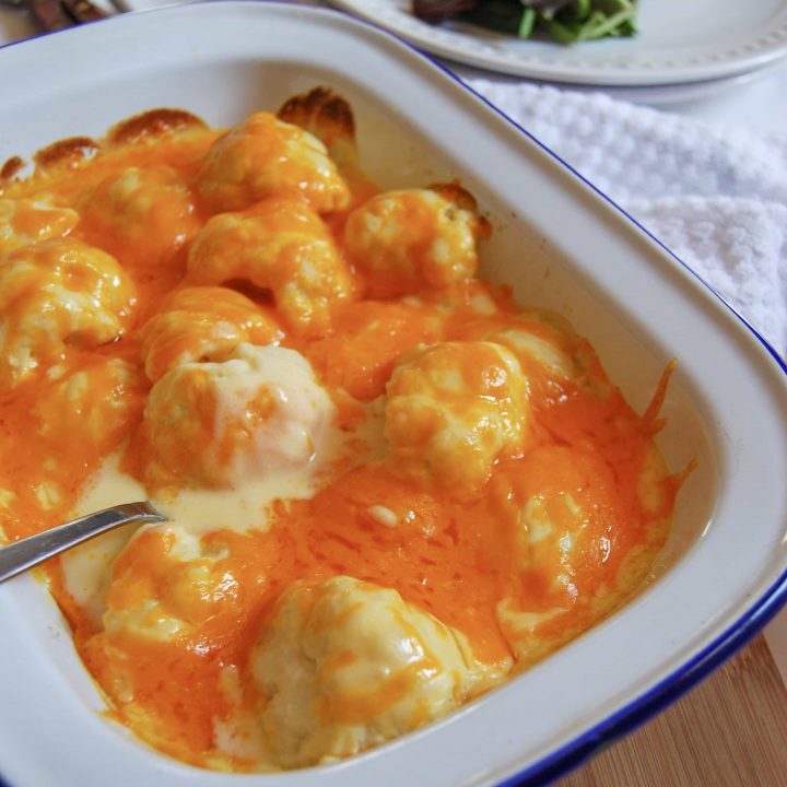 A white gratin dish filled with Creamy Cauliflower Cheese