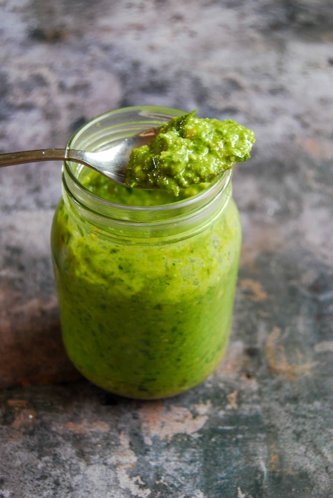 A jar of wild garlic pesto with a spoonful of pesto resting on top of the jar 