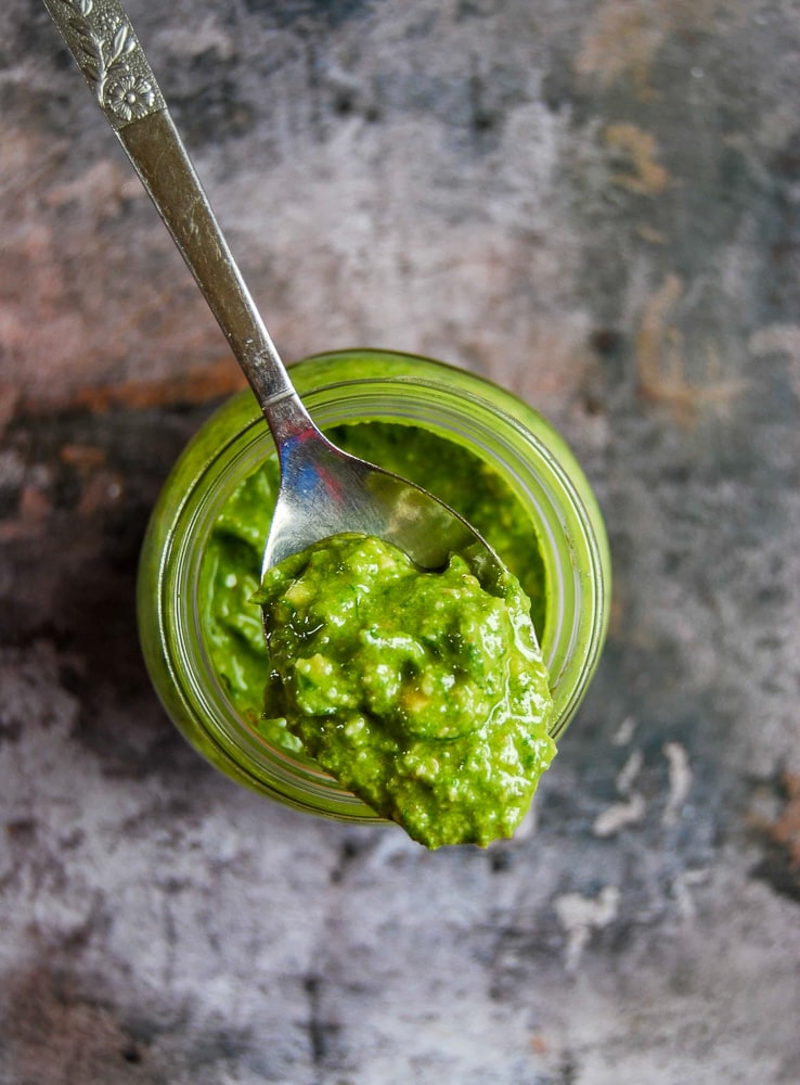 A spoonful of wild garlic pesto. The spoon is resting on top of the jar. 