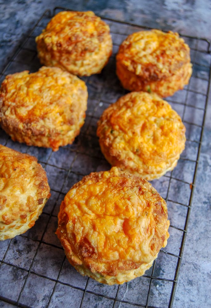 6 Cheese scones on a black cooling rack on a dark grey background.