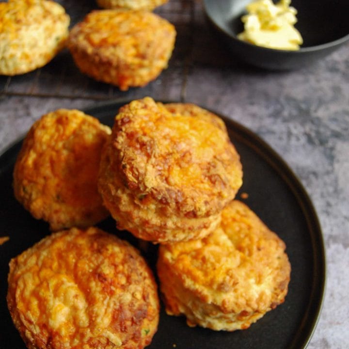 A pile of cheese scones on a black plate. The best cheese scone recipe ever!