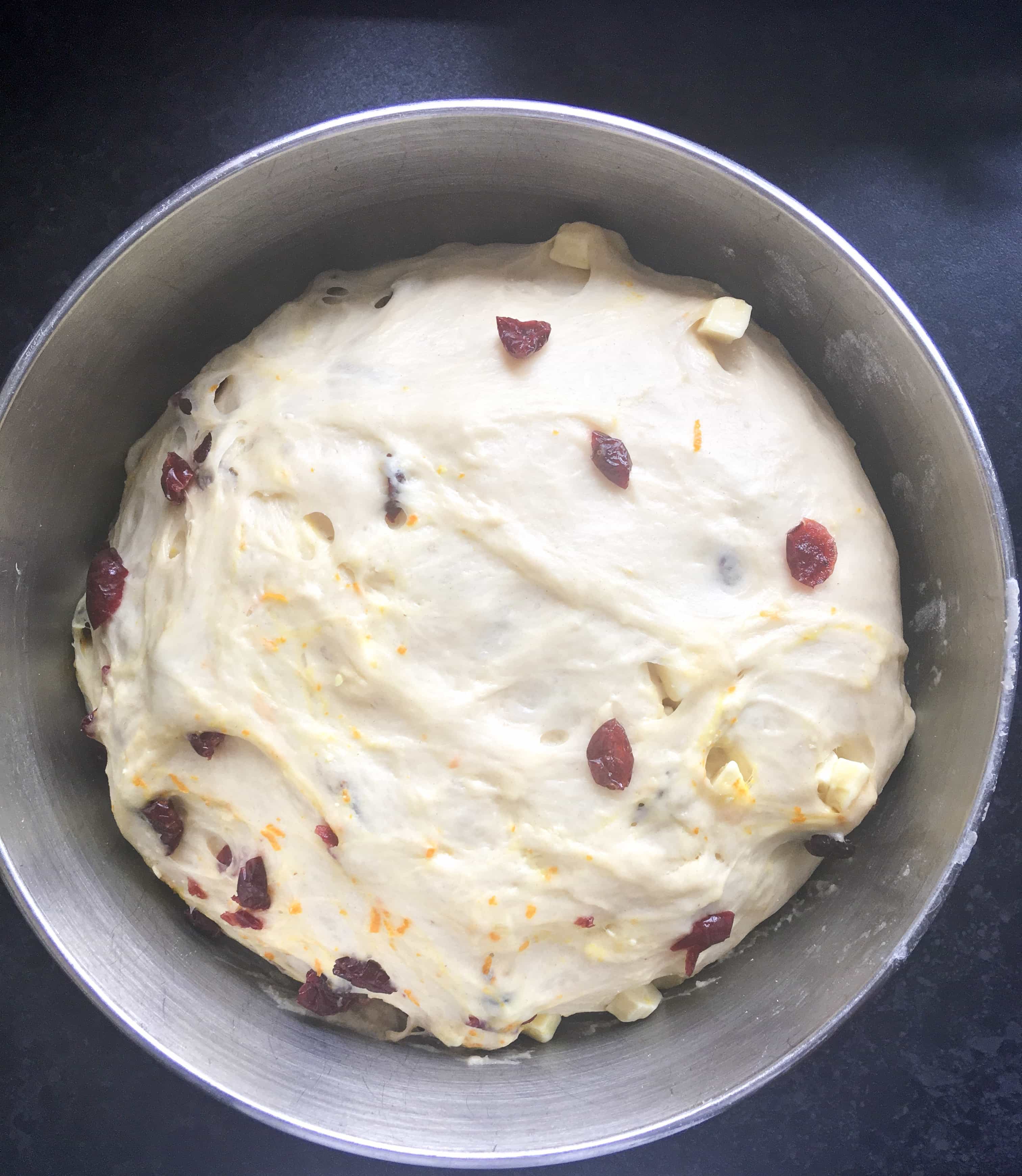 A bowl of fruity dough with cranberries, orange zest and chopped white chocolate.