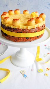 A slice of Easter Simnel cake topped with a marzipan ball on a floral plate.