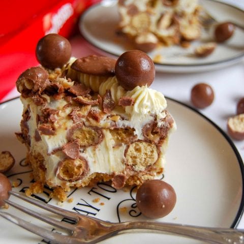 A slice of Mini Malteser Cheesecake For Two on a white and black plate.