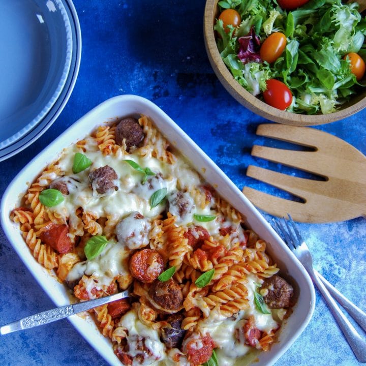Meatball Mozzarella Pasta Bake with plates and salad on the side