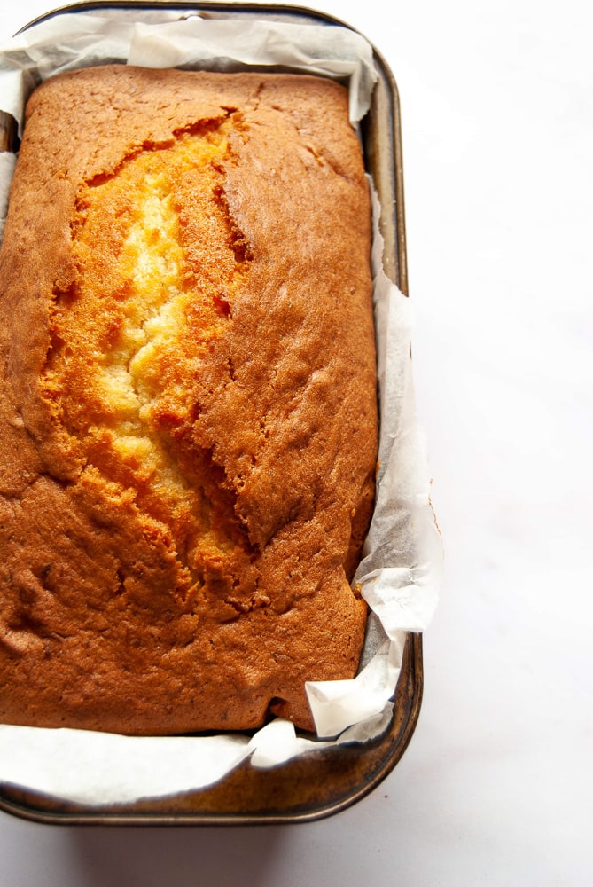 A close up flat lay picture of a freshly baked coconut loaf cake on a clean white background