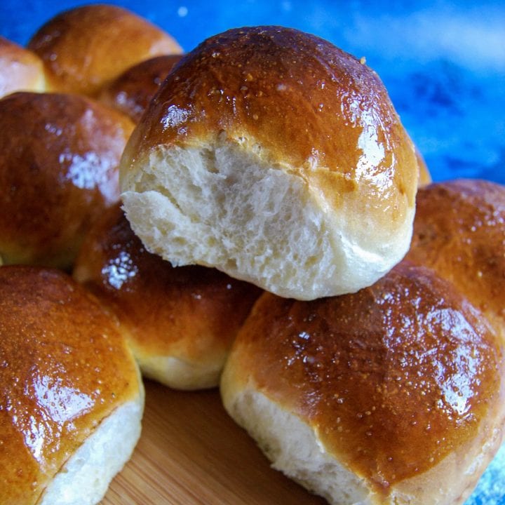 Soft and fluffy brioche burger buns on a wooden board/blue background.