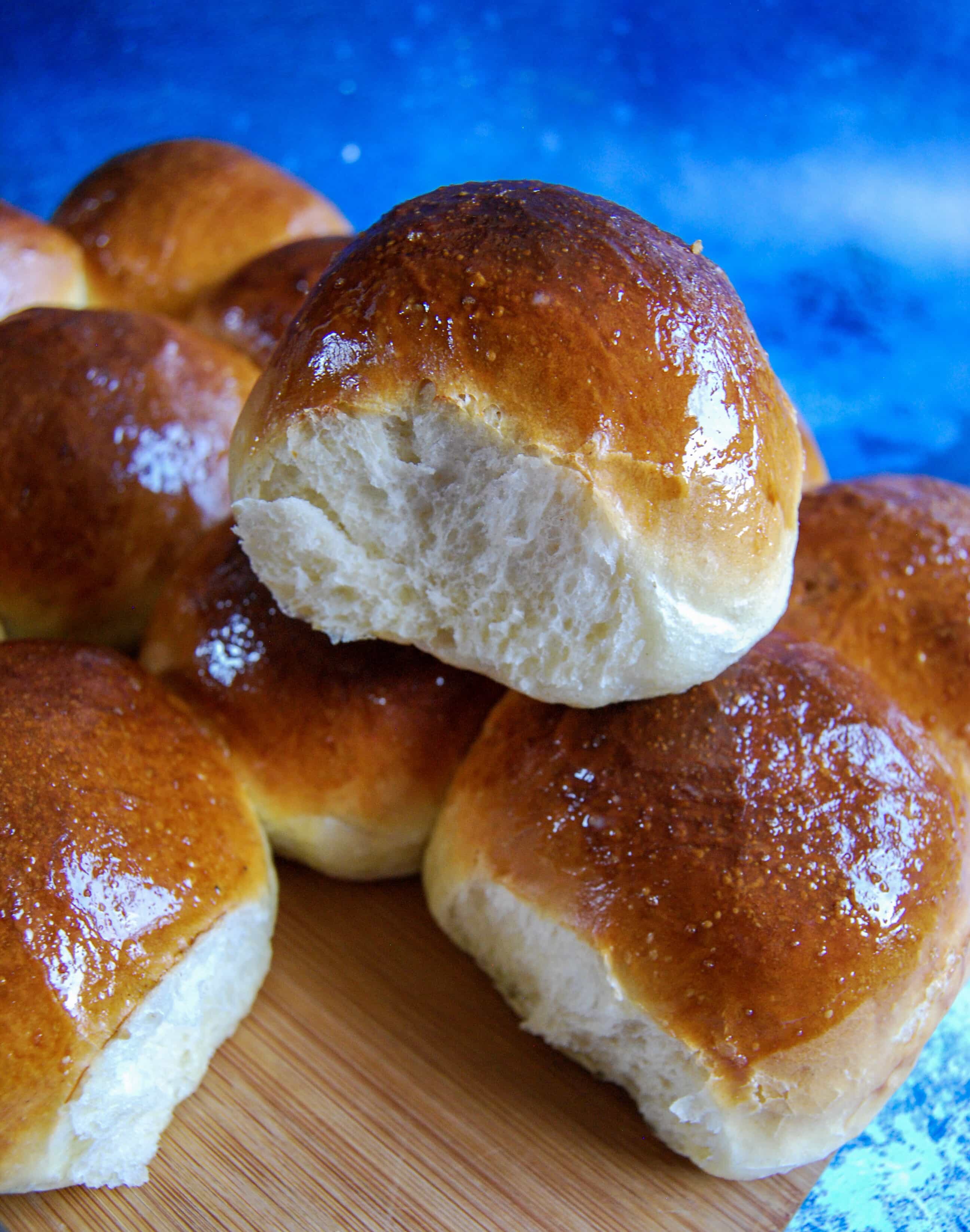 Soft and fluffy brioche burger buns on a wooden board/blue background.