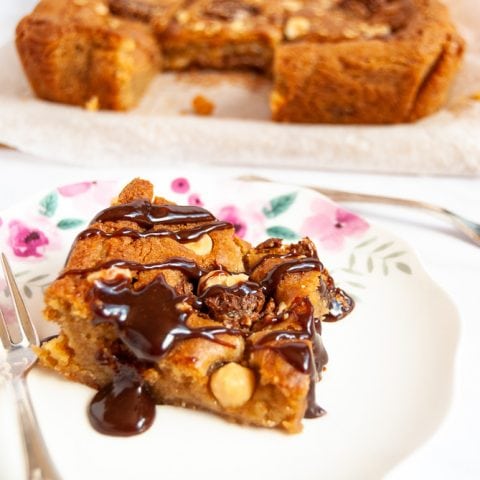 A Ferrero rocher blondie drizzled with a Nutella glaze on a white floral place