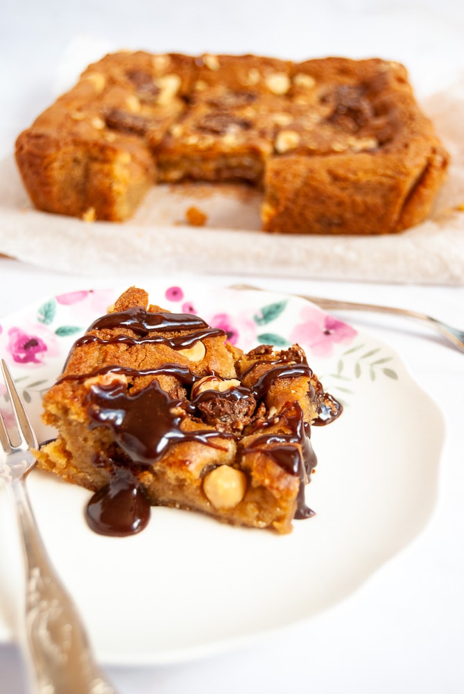 A Ferrero Rocher Blondie on a white floral plate covered in Nutella glaze. 