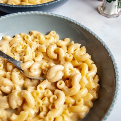 a light blue bowl of slow cooker mac and cheese on a white background