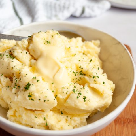 A bowl of creamy mashed potatoes with a pat of butter melting on top