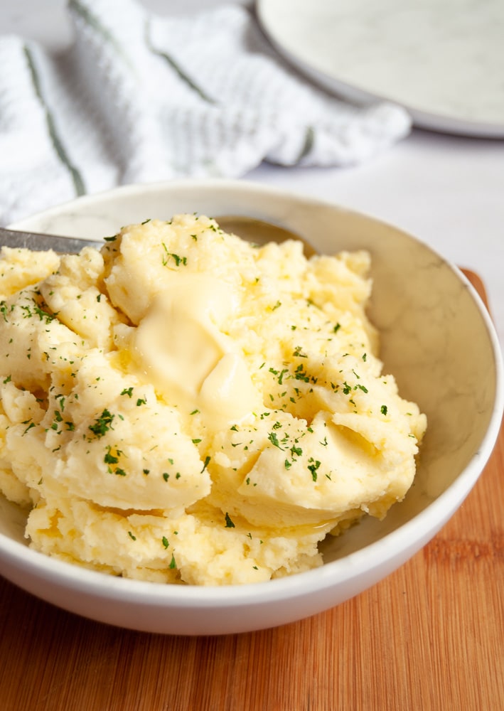 A bowl of creamy mashed potatoes with a pat of butter melting on top